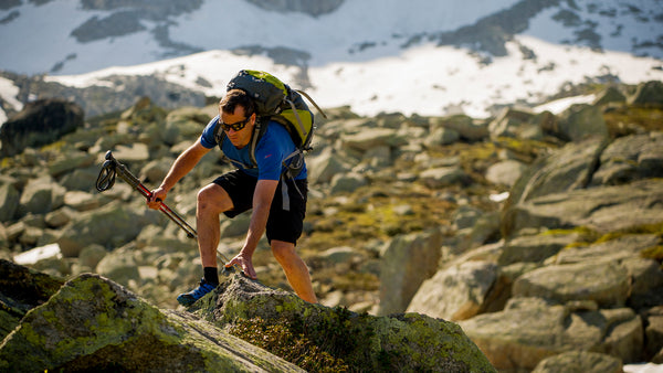 Man scrambling over rocks whilst trekking in the mountains