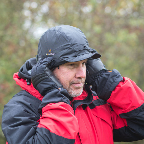 Lifestyle image of a man placing on his head an Extremities waterproof winter ice cap in black