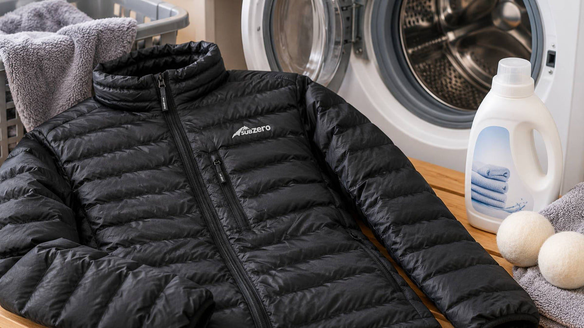 Black Sub Zero down jacket laid beside an open washing machine, with down wash detergent, towels and drying balls ready for cleaning and drying