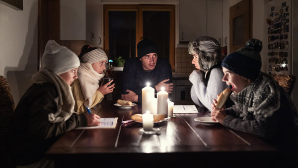 Family of five sitting around a table in winter using candlelight after a power cut