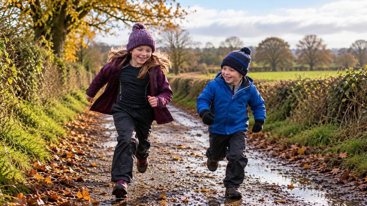 Children wearing warm layered outdoor clothing running along a muddy country lane on a cold autumn day.