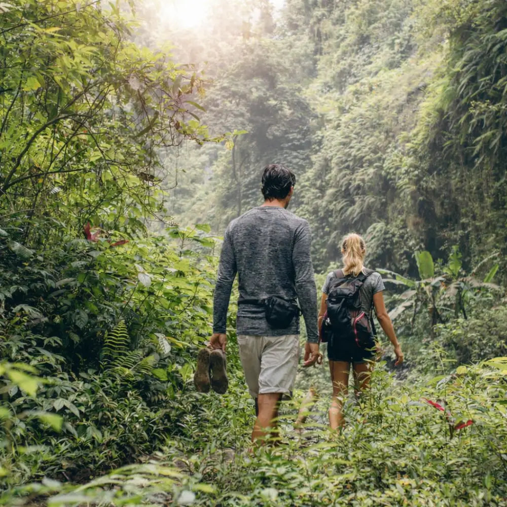 Man and a woman trekking through the jungle wearing  Sub Zero anti-mosquito summer base layer tops