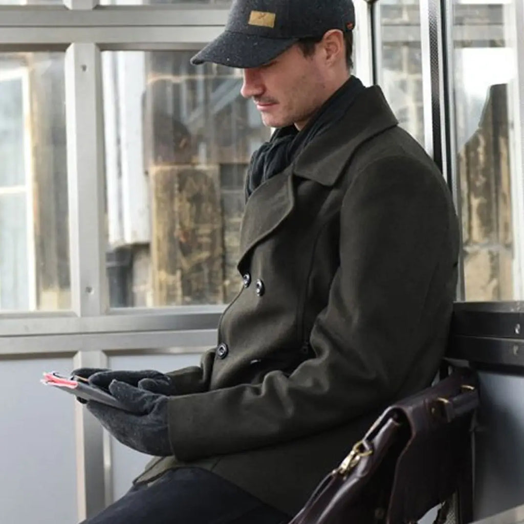 Lifestyle shot of a man waiting at a bus stop whilst commuting to work wearing a pair of Extremities Furnace Pro gloves 