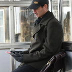 Lifestyle shot of a man waiting at a bus stop whilst commuting to work wearing a pair of Extremities Furnace Pro gloves 