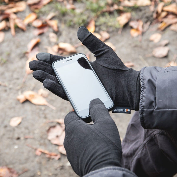 Lifestyle shot of a person outdoors wearing a pair of Extremities Merino Touchscreen Liner Gloves whilst using their phone