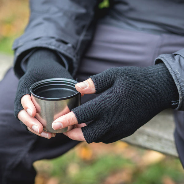 Lifestyle photograph of a man outdoors holding a flask mug whilst wearing Extremities Thinny fingerless gloves