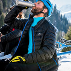 Lifestyle image of a male cyclist drinking from a water bottle whilst wearing a Sub Zero Factor 1 Plus mens long sleeve zip neck thermal base layer top aqua colour