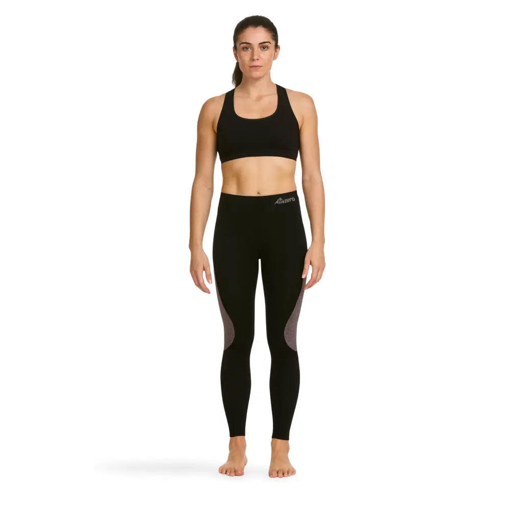 Woman wearing black athletic sports top and Sub Zero Factor 1 Plus stretch base layer leggings in black and pink on a white background