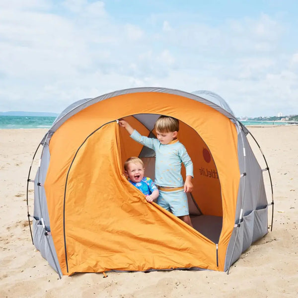 Lifestyle image of two toddlers inside the Littlelife family beach shelter playing with the zipped door whilst by the seaside