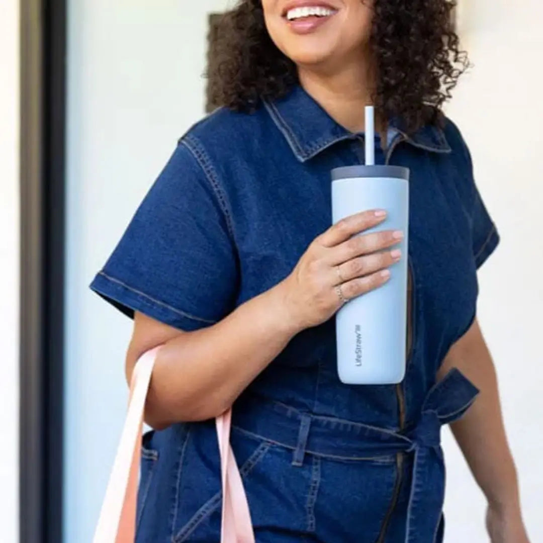 A lifetysle image of a woman holding a Lifestraw Go Series 500ml insulated stainless steel water filter tumbler in her hand