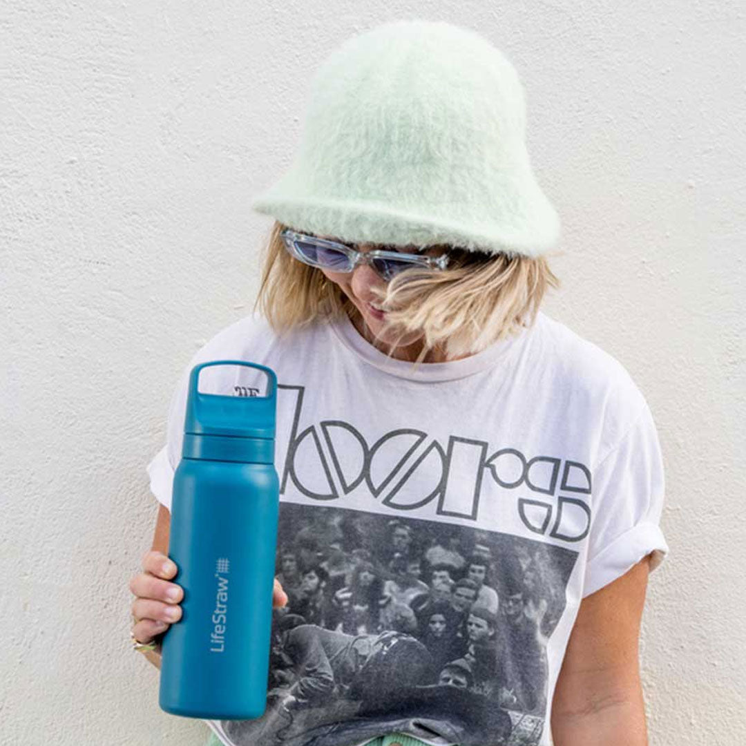 Lifestyle image of a girl holding a LifeStraw 1000ml vacuum insulated stainless steel Go Series water filter outdoors 