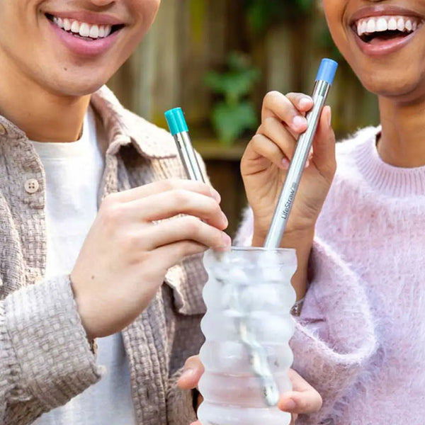 Lifetysle image of two people using Lifestarw sip water filter straws to drink from a glass of water