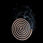 Lit single Lifesystems insect repellent coil showing the smoke production on a black background