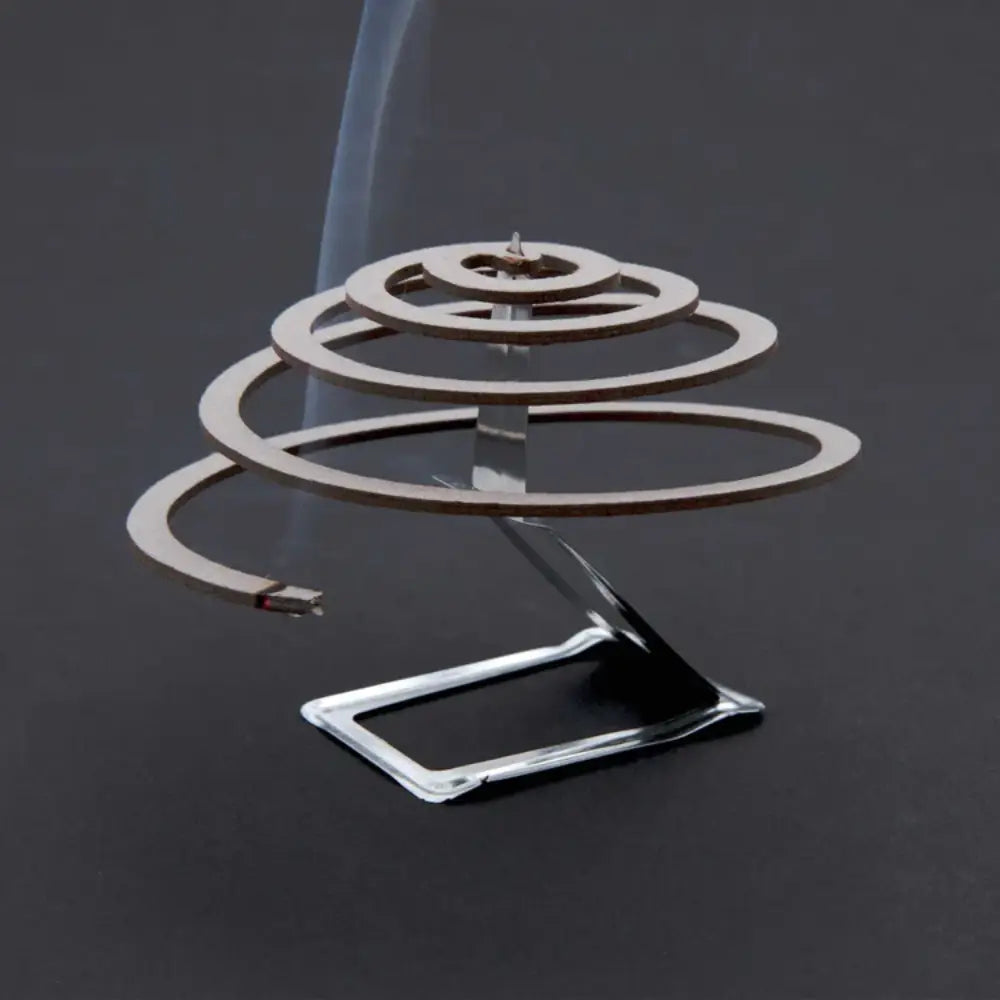 Lit single Lifesystems insect repellent coil on its burning stand on a grey background 