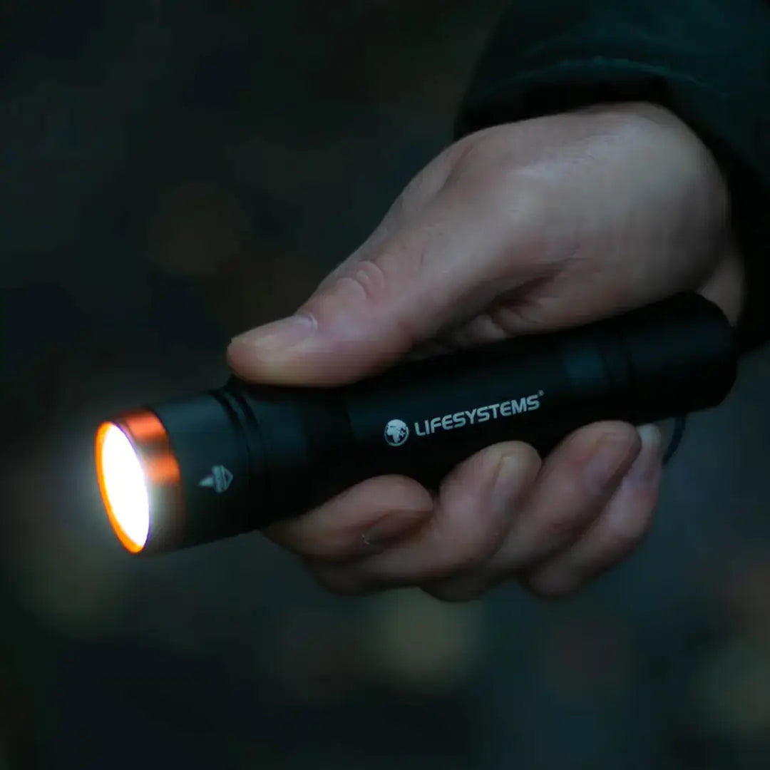Man holding a Lifesystem Intensity 545 torch in his right hand at night whilst turned on