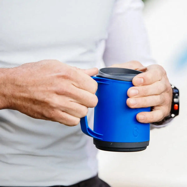 Lifestyle shot of a Lifeventure Ellipse insulated camping mug being held in two hands by a man