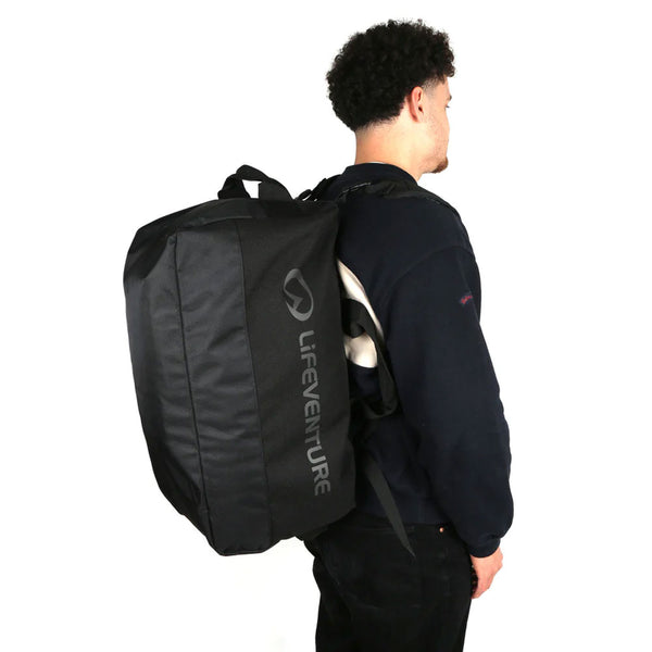 A man wearing a Lifeventure Expedition Cardo duffle bag on his shoulders in the backpack version