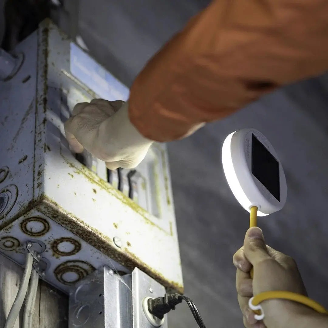 Lifestyle image of a person using a Luci portable solar powered light fixed around their wrist to perform maintenance on a circuit board in the dark 