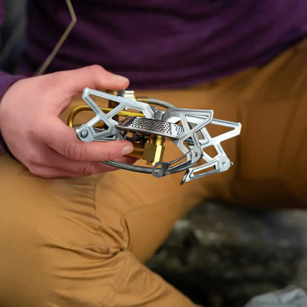 Person holding a Primus Gravity Camping Gas Stove wit the pot legs folded in an outdoor setting