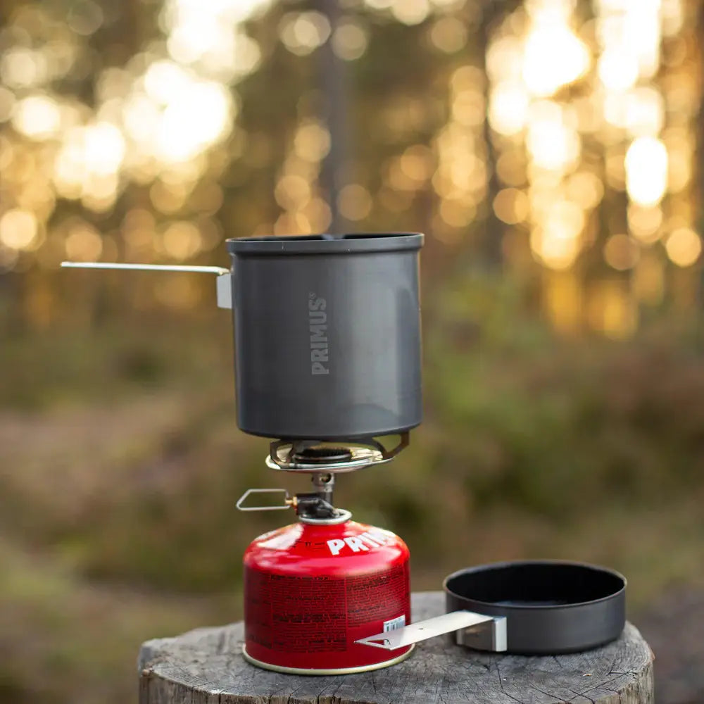 Primus Trek pot being used with a camping gas stove in a forest setting.