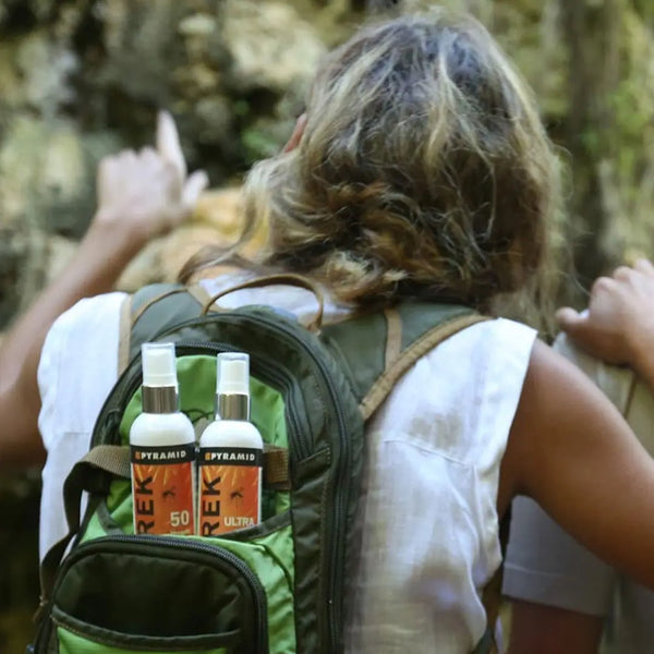 Pyramid Trek Ultra 30% deet mosquito repellent spray bottles in the back of a womans backpack during a jungle trek