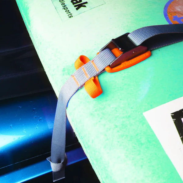 Close-up of a Sea To Summit 3 metre orange bomber strap holding  a green surfboard down on to a car roof rack