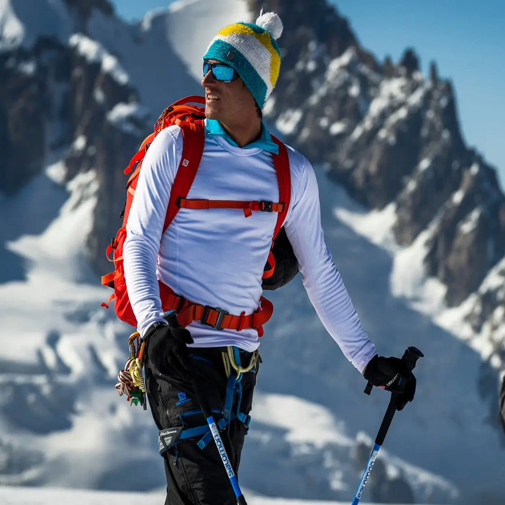 Lifestyle shot in the alps of a man wearing a white Sub Zero Factor 2 mens mid layer thermal top whilst skiing