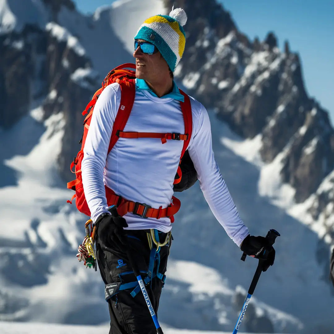 Lifestyle shot in the alps of a man wearing a white Sub Zero Factor 2 mens mid layer thermal top whilst skiing