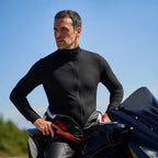 Man straddling his motorbike with his upper leathers peeled back to show the Sub Zero Factor 2 thermal mid layer onesie in black worn underneath