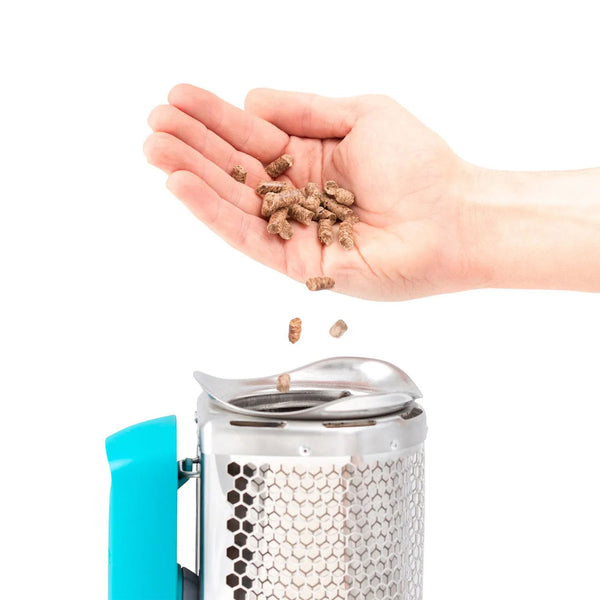 Studio shot on a white background of a hand dropping in BioLite premium BioFuel hardwood pellets in to the hopper of a Biolite Camp Stove 2