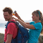 Lifestyle image of a woman applying Care Plus Sun Cream on to a mans neck when outdoors in the sun