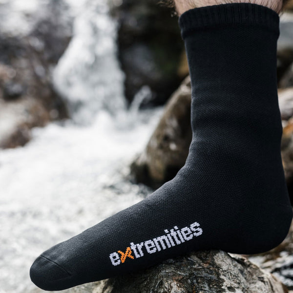 Lifestyle photograph of a Extremities Evolution Waterproof Sock being worn next to a stream