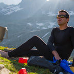 Man wearing Sub Zero Factor 1 Plus leggings and base layer top in black seated on the ground whilst camping in the mountains
