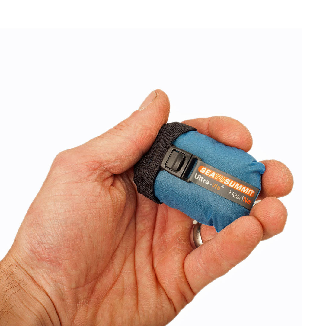 A hand holding a packed Sea To Summit Nano head net showing the compact size 