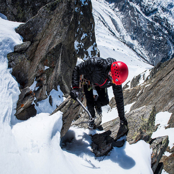Lifestyle photograph of a man climbing in the snow covered alps wearing a Sub Zero lightweight down jacket and Factor 2 Plus mid layer leggings