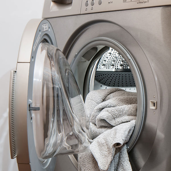 Studio shot of a washing machine with its door open and a towel hanging out